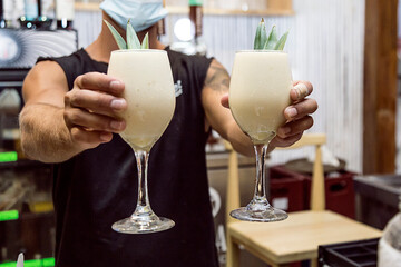 Bartender showing the customer the drink he has just prepared. Night club or party atmosphere. Classy drinks.