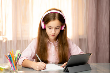 A teenage girl learns online from home. Education.