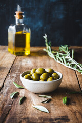 aceitunas variedad manzanilla en un bol, con una rama de olivo y una aceitera de vidrio con aceite...