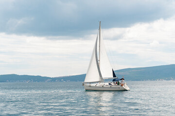 Naklejka premium A large white sailing yacht for tourists in a blue sea against a clear sky. Tourist sailing boat. Water transport for tourists.
