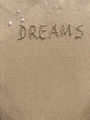 on the beach is carved with letters in the smooth sand the writing Dreams