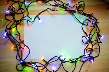 A frame of Christmas garlands on a wooden table. Space for text.