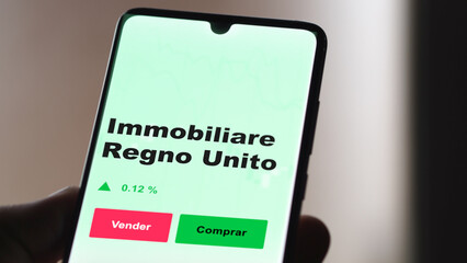 Un inversor está analizando el immobiliare regno unito etf fondo en pantalla. Un teléfono muestra los precios del ETF para invertir. Texto en español.