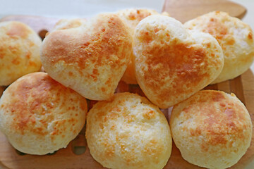 Pile of Freshly Baked Homemade Pao de Queijo or Brazilian Cheese Breads with a Pair of the Heart Shaped on Top