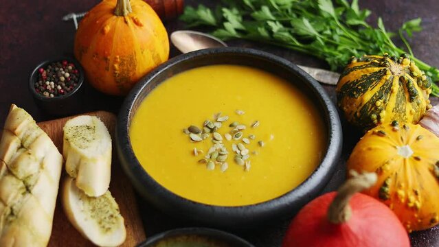 Delicious pumpkin soup with cream sumflower seeds and garlic toasts on dark rusty background