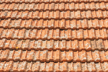 Old orange tiles on the roof of the house. The old ceramic coating of the roof of the house from water and moisture. Tile close-up.