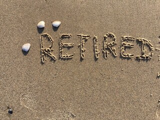 on the beach is carved with letters in the smooth sand the writing Retired