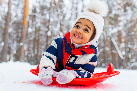Winter portrait of happy little girl wearing knitted hat and a jumpsuit outdoor in winter