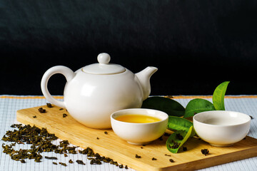 A small teapot with bowls and green tea on a bamboo stand