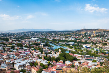 Fototapeta na wymiar Tbilisi cityscape in summer, Georgia. Top view over the city center and Kura river in Tbilisi. Aerial view of the Georgian capital