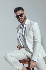attractive bearded businessman with sunglasses wearing white suit