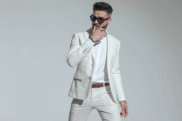 sexy fashion businessman in white suit sensually touching lips