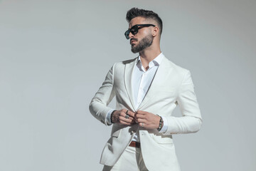 Fototapeta bearded businessman with sunglasses buttoning white suit obraz