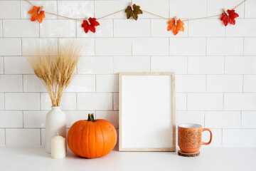 Frame mockup with autumn fall home decor, pumpkins, cup of coffee, candle in cozy home interior. Fall poster design. Halloween or Thanksgiving concept.