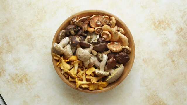 Various kinds of assorted raw mushrooms placed in wooden bowl