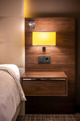 Gemütliches Schlafzimmer mit Nachttischlampe und Wand in Holzdekor