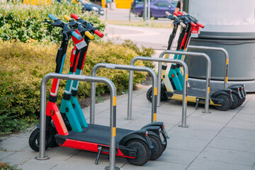 Public share service. Mobile transport. City vehicle. Colorful electric scooters in parking zone on street daylight.
