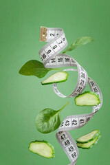 White measuring tape with pieces of vegetables and herbs on a green background