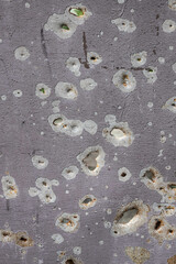 Bullet marks. A fence cut by shrapnel. Iron, pierced by shells. War in Ukraine. Russian aggression. Shooting civilians. Mutilated housing.