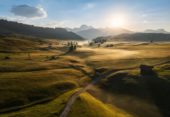 Sunrise with fog and mist in the Dolomites mountains of the Alps in Italy. High mountains pastures with cottages and roads. 