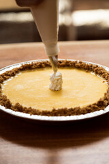 Woman preparing a cheesecake. She is putting cream on it to give it the final touch.