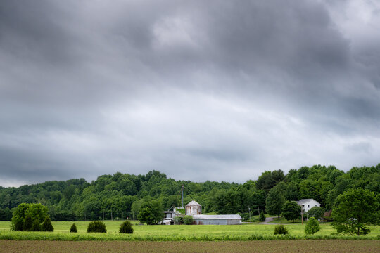 A farm in Indiana on a rainy and cloudy day. The image is mostly greens and greys