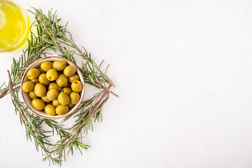 Green marinated olives in a bowl with rosemary. Copy space, top view