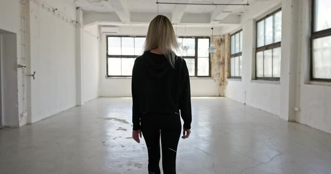 Camera following blonde woman walking in industrial interior
