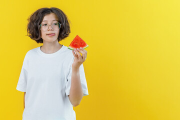 teenage girl with glasses holds in her hand piece of watermelon on colored background, design of advertising banners, business cards and layout, copy space, studio photo