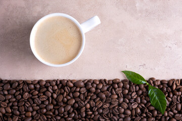 Top view with place for text roasted coffee beans border and cup of coffee on a light brown background.