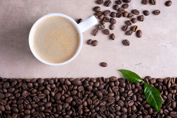 Top view with place for text roasted coffee beans border and cup of coffee on a light brown background.