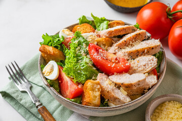 Caesar salad. Healthy salad made of chicken breast fillet, lettuce, tomatoes, quail eggs, croutons, parmesan cheese