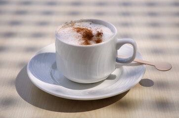Ein Tasse mit Latte macchiato, Cafe Latte steht auf einem Tisch.
