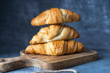 Fresh fragrant croissants lie on a cutting board. Close-up. Home baking, bakery.