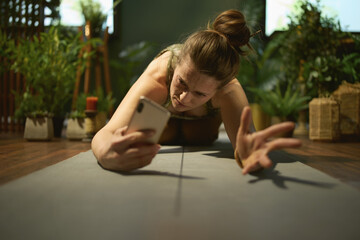 stressed stylish woman at green home stretching and using phone