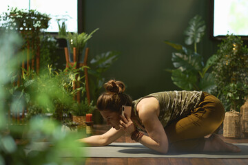 female in green house stretching and talking on phone