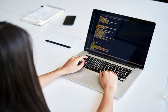 Female programmer writing code at office using laptop
