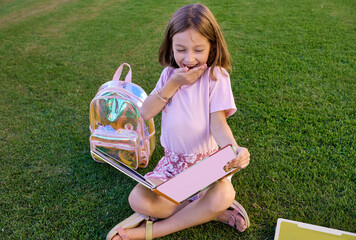 girl sitting on the grass reading a book having fun and learning outdoors