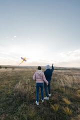 A happy couple flies a kite and spends time together outdoors in a nature reserve. Happy relationships and family vacations. Freedom and space.