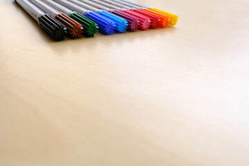 Fototapeta premium school background, colored felt-tip pens lie on a light table, close-up, the concept of student writing supplies, back to school