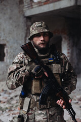 A Ukrainian military man poses against the background of destroyed buildings. The war between Ukraine and Russia