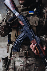 A soldier is holding an assault rifle, close-up.