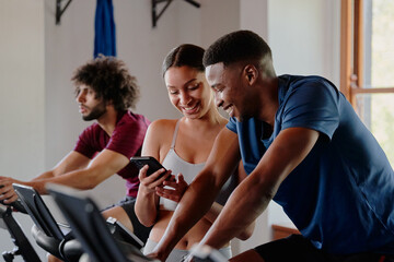 Fototapeta na wymiar Group of happy young multiracial friends using mobile phone at the gym