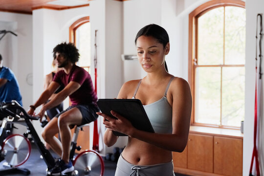 Professional biracial young woman using digital tablet at the gym