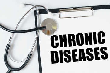 On a white surface, a stethoscope and a tablet with an inscription - CHRONIC DISEASES