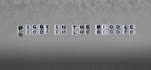 piggy in the middle word or concept represented by black and white letter cubes on a grey horizon...