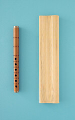 Brown flute and bamboo asura on blue background. Colorful minimalism. Minimal music layout concept.
