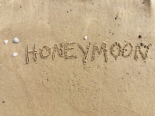 on the beach is carved with letters in the smooth sand the writing Honeymoon