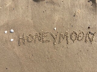 on the beach is carved with letters in the smooth sand the writing Honeymoon