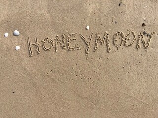 on the beach is carved with letters in the smooth sand the writing Honeymoon